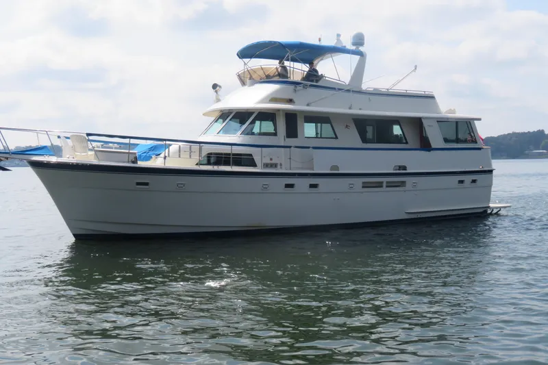 Slide: The Image of 1986 Hatteras 58 Motor Yacht on calm water, featuring a classic design and spacious deck. - 2