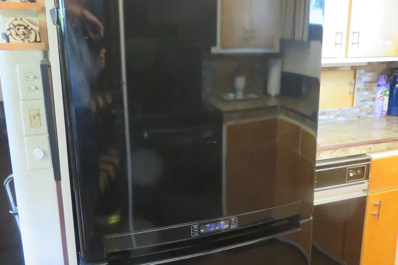 Slide: The Image of Black refrigerator in a kitchen aboard a 1986 Hatteras 58 Motor Yacht. - 25