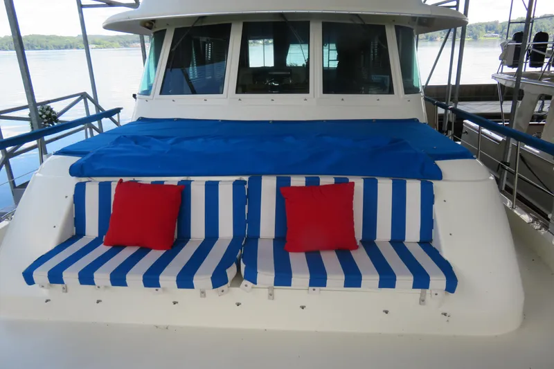 Slide: The Image of 1986 Hatteras 58 Motor Yacht with blue-striped seating and red cushions on deck. - 42