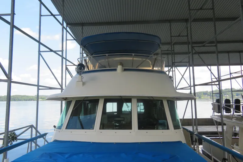 Slide: The Image of 1986 Hatteras 58 Motor Yacht docked under a covered marina with scenic lake view. - 43