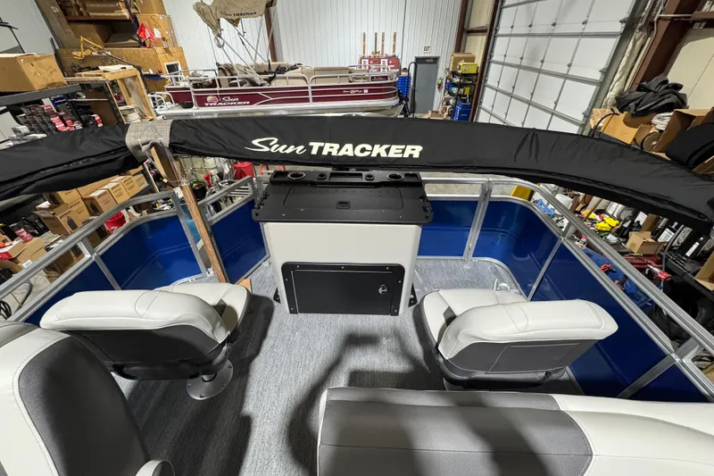 Slide: The Image of 2026 Sun Tracker Fishin' Barge 20 DLX interior with seating and console in a garage. - 10