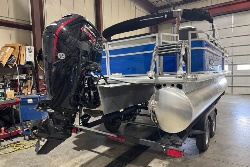 Slide: The Image of 2026 Sun Tracker Fishin' Barge 20 DLX pontoon boat with Mercury outboard motor in a garage. - 3