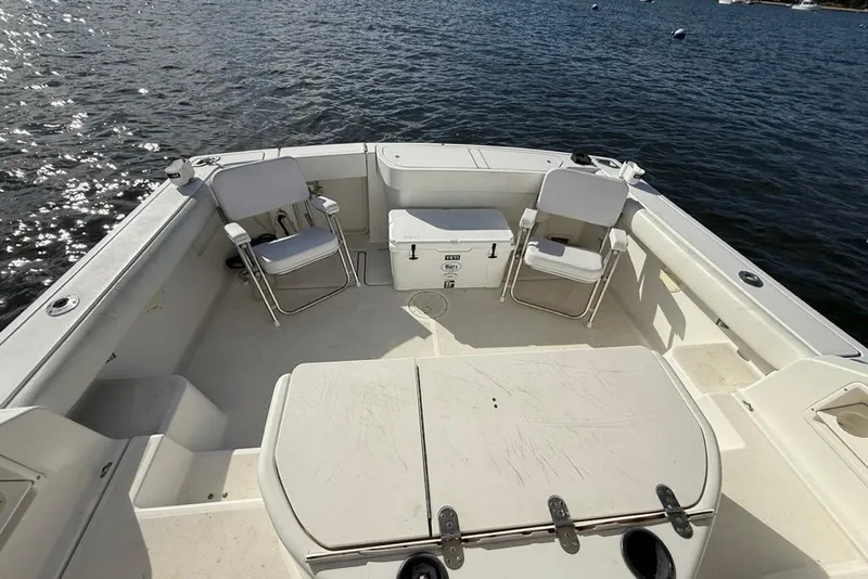 Slide: The Image of 2003 Pursuit 3000 Offshore boat deck with chairs and cooler on water. - 11