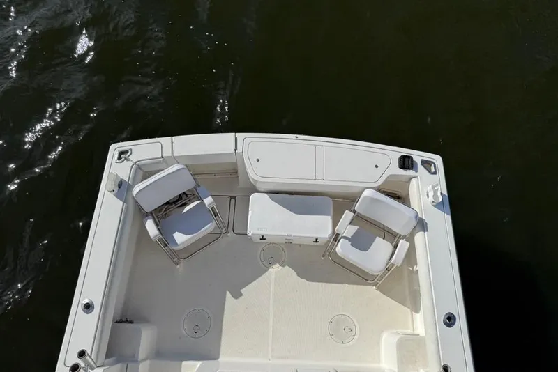 Slide: The Image of 2003 Pursuit 3000 Offshore boat deck with chairs and storage, on calm water. - 14