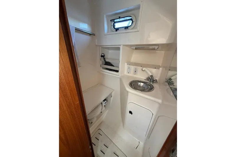 Slide: The Image of 2003 Pursuit 3000 Offshore boat bathroom with sink, toilet, and window. - 15