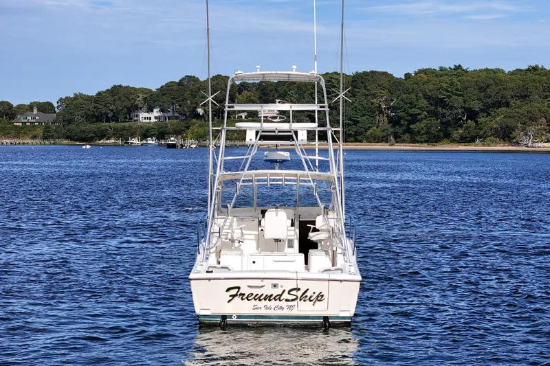 Slide: The Image of 2003 Pursuit 3000 Offshore boat on calm water, surrounded by lush greenery. - 4