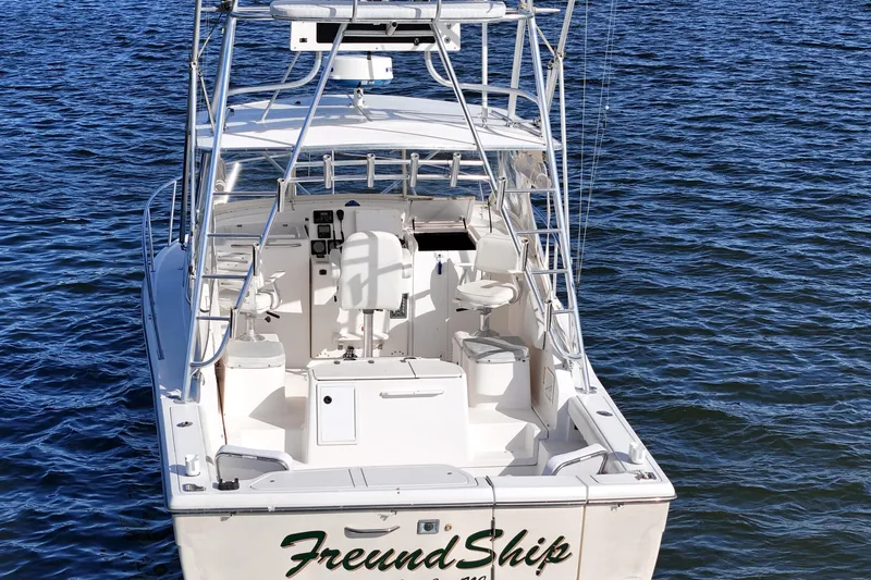 Slide: The Image of 2003 Pursuit 3000 Offshore boat on water, rear view, white exterior, open cockpit. - 5
