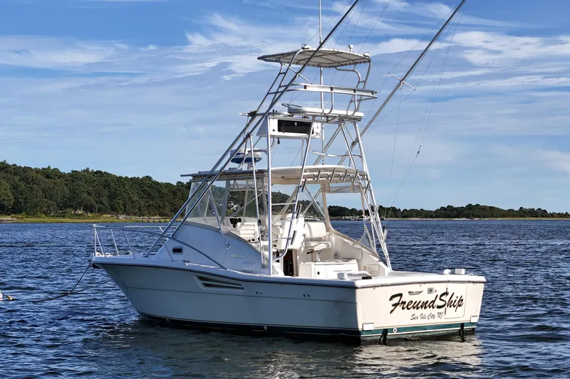 Slide: The Image of 2003 Pursuit 3000 Offshore boat anchored on calm water with scenic background. - 7