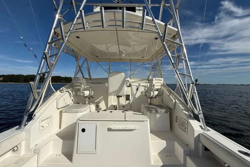 Slide: The Image of 2003 Pursuit 3000 Offshore boat interior with fishing equipment, under a clear blue sky. - 9