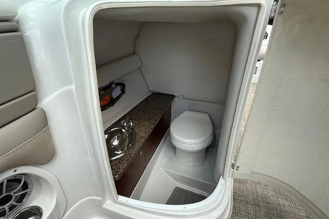Slide: The Image of 2018 Crownline 255 SS boat interior with compact bathroom, featuring a toilet and sink. - 29