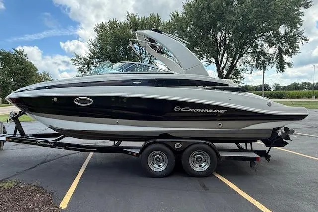 Slide: The Image of 2018 Crownline 255 SS boat on trailer, parked outdoors under cloudy sky. - 3