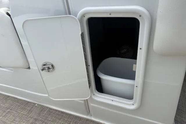 Slide: The Image of Open storage compartment on 2018 Crownline 255 SS boat, featuring a white interior bin. - 33