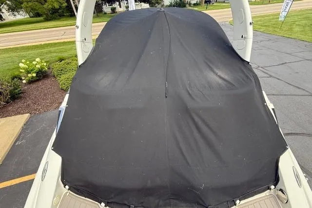 Slide: The Image of 2018 Crownline 255 SS boat with black cover, parked on pavement. - 38