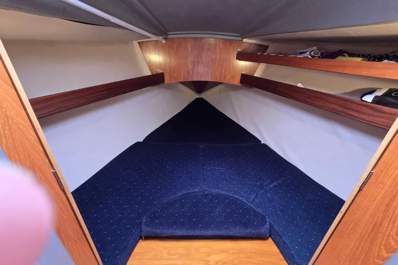 Slide: The Image of Cozy cabin interior of 1991 Beneteau 35.5 S5 sailboat with blue bedding and wooden shelves. - 12