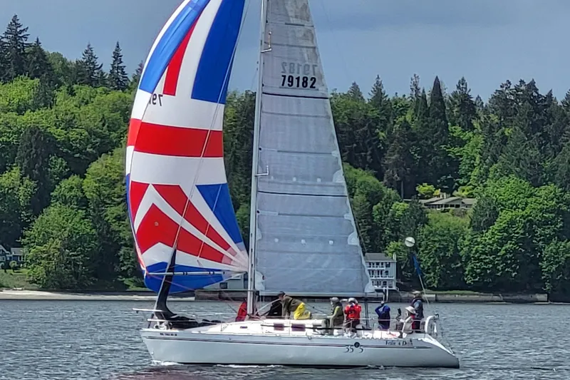Slide: The Image of Sailing yacht Beneteau 35.5 S5, 1991, with colorful spinnaker on a scenic lake. - 2