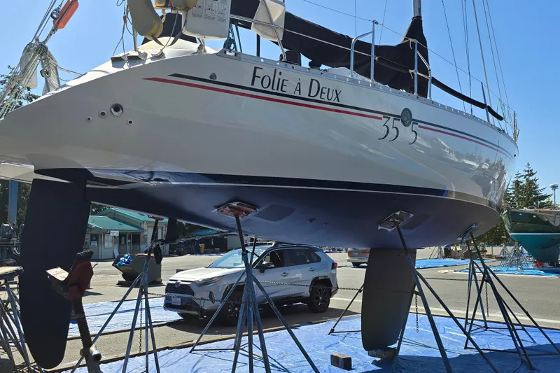 Slide: The Image of 1991 Beneteau 35.5 S5 sailboat on stands, named "Folie À Deux," in a boatyard. - 27