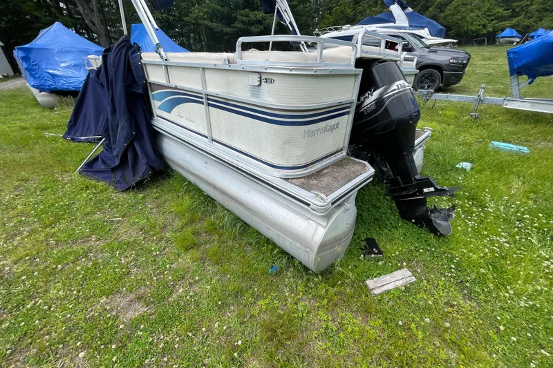 Slide: The Image of 1999 Harris Super Sunliner 240 pontoon boat on grassy area with outboard motor. - 12