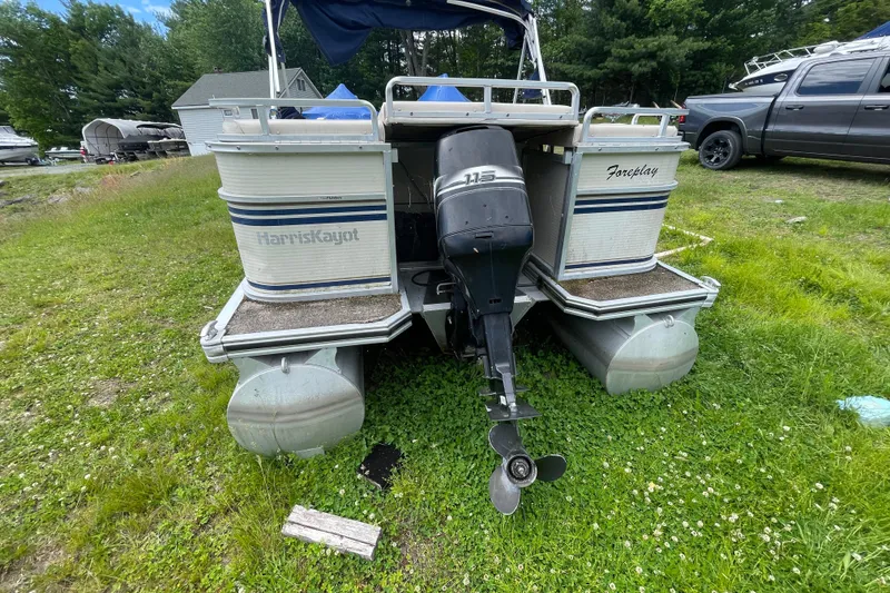 Slide: The Image of 1999 Harris Super Sunliner 240 pontoon boat with outboard motor on grassy area. - 4
