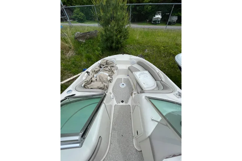 The Image of 2002 Sea Ray 210 Sundeck boat interior with seating and storage, parked outdoors. - 0
