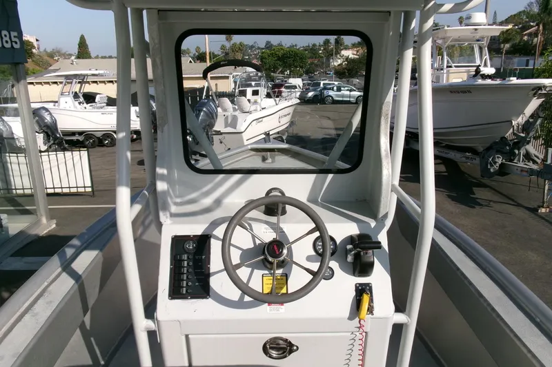 Slide: The Image of 2003 Pacific Boats 2025 V helm with steering wheel and controls, docked among other boats. - 10