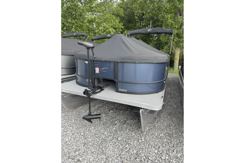 Slide: The Image of 2025 Crest Classic Fish 220 pontoon boat with cover, parked on gravel. - 28