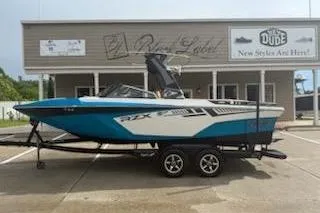 Slide: The Image of 2017 Tigé RZX2 boat on trailer, parked outside a building. - 2