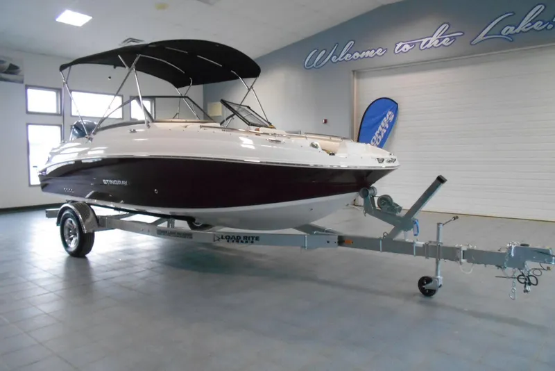 Slide: The Image of 2025 Stingray 201 DC boat on trailer in showroom, under "Welcome to the Lake" sign. - 4