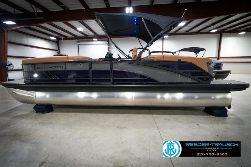 Slide: The Image of 2026 Bennington 22 MFB pontoon boat in showroom with canopy and tan seating. - 10