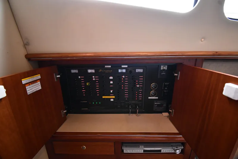 Slide: The Image of 2007 Cruisers Yachts 455 Express Motoryacht electrical panel with open wooden cabinet doors. - 54
