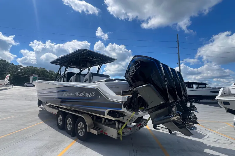 Slide: The Image of 2023 Nor-Tech 390 Sport boat with triple engines on a trailer under a blue sky. - 3
