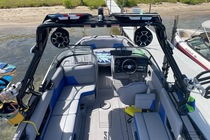 Slide: The Image of 2023 Moomba Max boat interior with modern seating, speakers, and control panel at a dock. - 16