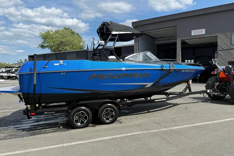 Slide: The Image of 2023 Moomba Max boat in vibrant blue on a trailer, parked outdoors. - 3