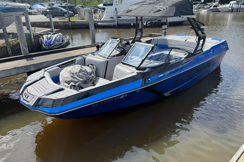 Slide: The Image of 2023 Moomba Max boat docked in a marina, featuring sleek blue design and spacious seating. - 5