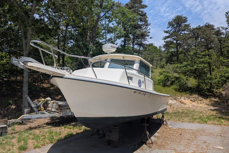 The Image of 2008 Parker 2520 Modified Vee Sport Cabin boat on land, surrounded by trees. - 0