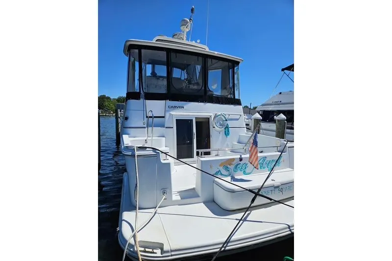 Slide: The Image of 2003 Carver 444 Cockpit Motor Yacht docked, featuring spacious deck and American flag. - 3