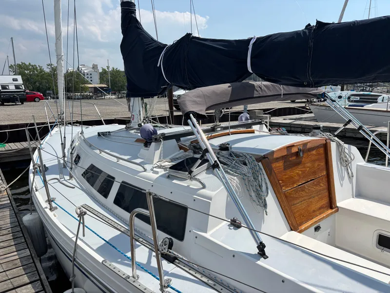 Slide: The Image of 1992 Catalina 34 sailboat docked, featuring a covered mast and wooden hatch. - 22