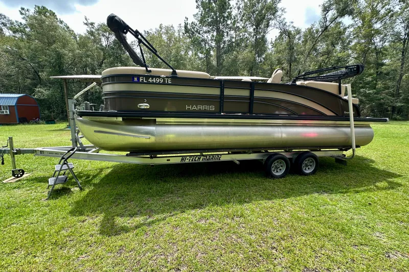 The Image of 2022 Harris FloteBote 230 Super Sunliner LX pontoon boat on trailer in grassy area. - 0