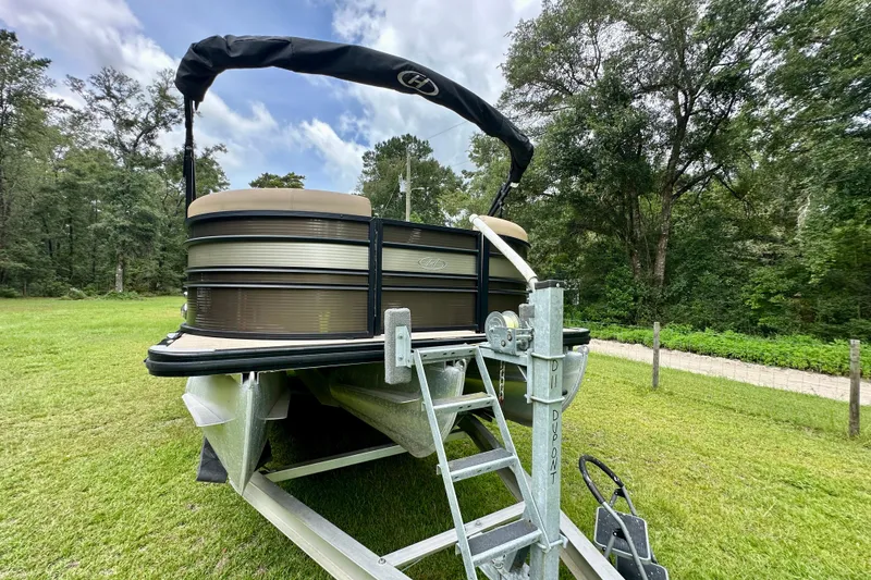 Slide: The Image of 2022 Harris FloteBote 230 Super Sunliner LX pontoon boat on trailer in grassy area. - 11