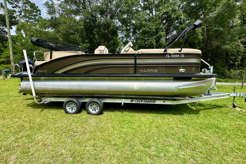 Slide: The Image of 2022 Harris FloteBote 230 Super Sunliner LX pontoon boat on trailer, parked on grass. - 2