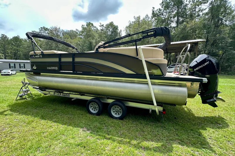 Slide: The Image of 2022 Harris FloteBote 230 Super Sunliner LX pontoon boat on trailer, parked on grass. - 7