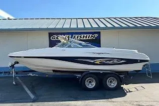 The Image of 2002 Rinker 212 Captiva boat on trailer, parked outside a building. - 1