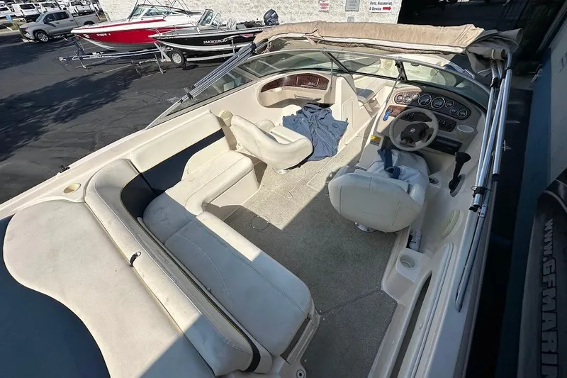 Slide: The Image of 2002 Rinker 212 Captiva boat interior with beige seating and steering wheel. - 12