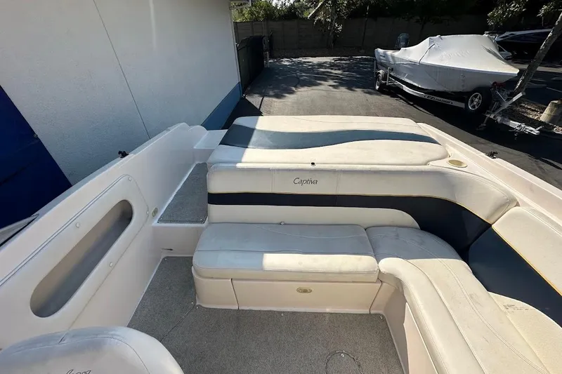 Slide: The Image of 2002 Rinker 212 Captiva boat interior with cushioned seating and carpeted flooring. - 13
