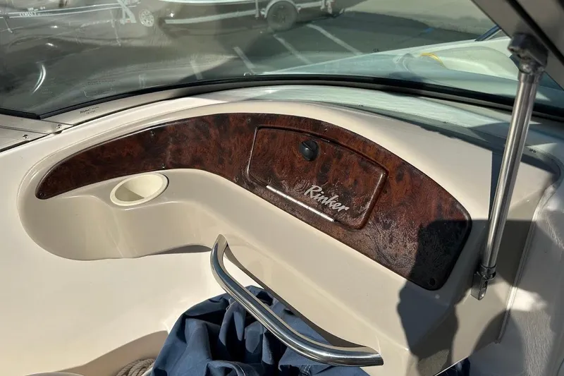 Slide: The Image of 2002 Rinker 212 Captiva boat dashboard with wood paneling and storage compartment. - 15