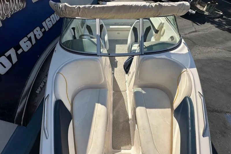 Slide: The Image of 2002 Rinker 212 Captiva boat interior with seating and windshield, parked outdoors. - 25