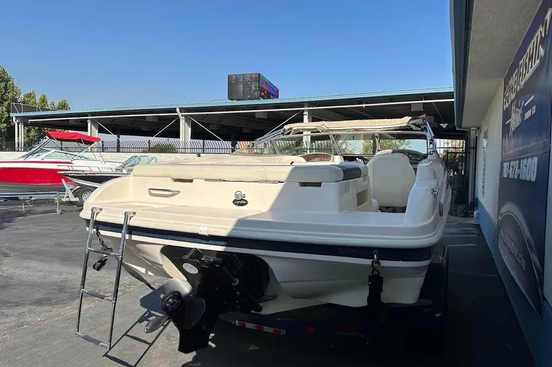 Slide: The Image of 2002 Rinker 212 Captiva boat with ladder, parked outdoors near dealership. - 8