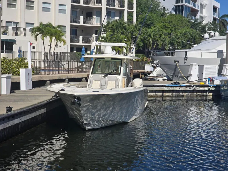 Slide: The Image of 2024 Scout 355 LXF boat docked in a marina, surrounded by modern buildings and greenery. - 10