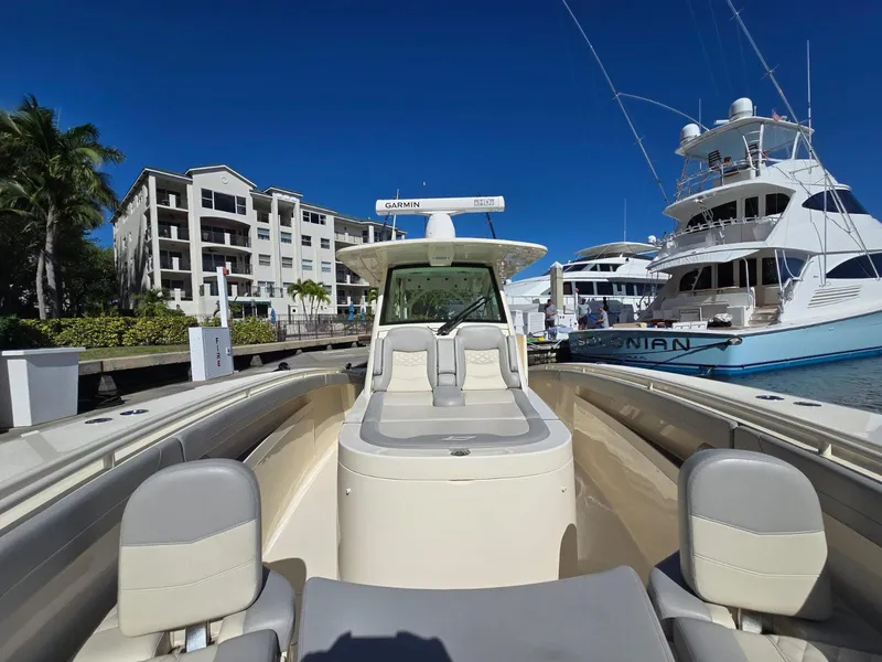 Slide: The Image of 2024 Scout 355 LXF boat docked at marina with luxury yachts and buildings. - 16