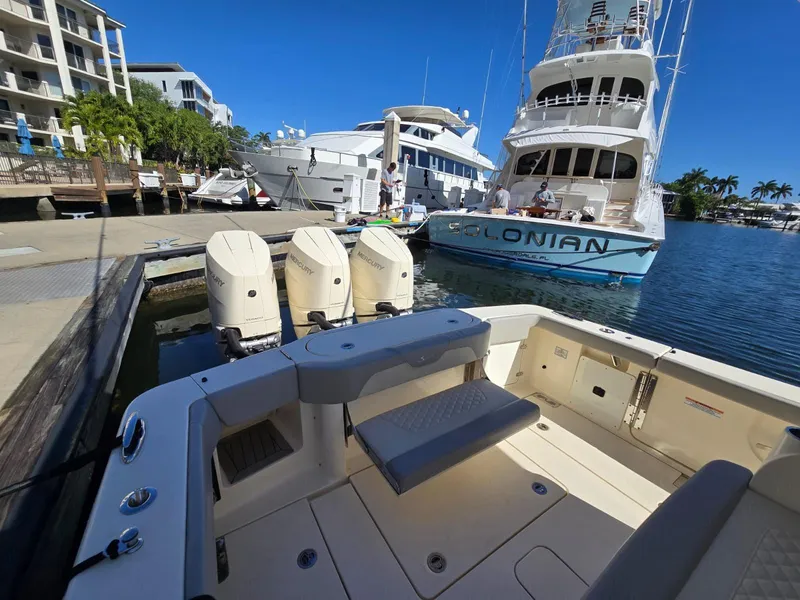 Slide: The Image of 2024 Scout 355 LXF boat docked with triple outboard engines, marina view. - 18