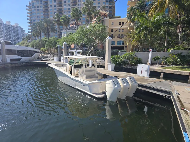 Slide: The Image of 2024 Scout 355 LXF boat docked in a marina with triple outboard engines. - 2